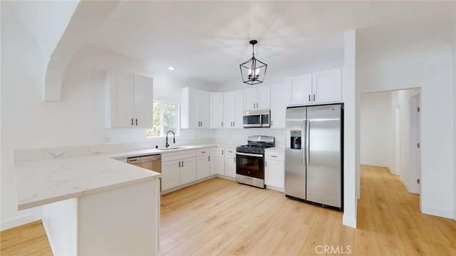 1113 Pacific Ave, Long Beach, CA 90813 - kitchen featuring appliances with stainless steel finishes, a peninsula, light wood finished floors, light stone counters, and recessed lighting