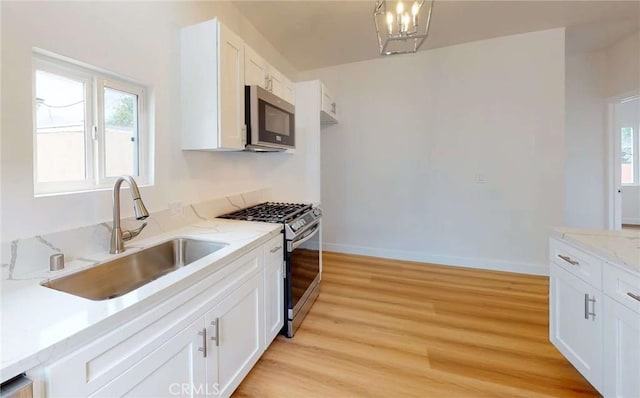 1113 Pacific Ave, Long Beach, CA 90813 - kitchen with appliances with stainless steel finishes, white cabinetry, light wood-type flooring, and light stone countertops