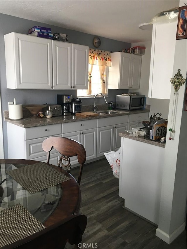 16472 Vine St, Hesperia, CA 92345 - kitchen featuring stainless steel microwave, dark wood finished floors, white cabinetry, and dark countertops