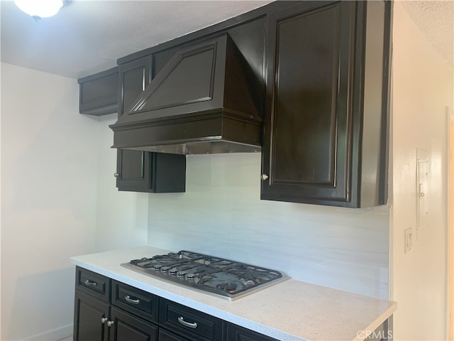 14299 La Paz Dr Unit 6, Victorville, CA 92395 - kitchen featuring stainless steel gas stovetop, premium range hood, light countertops, and decorative backsplash