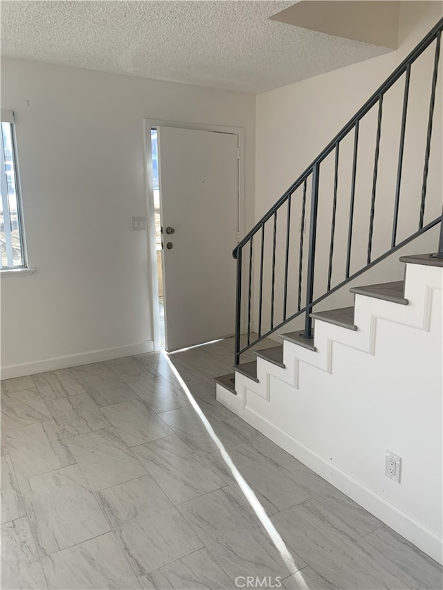 14299 La Paz Dr Unit 6, Victorville, CA 92395 - foyer featuring stairs, a textured ceiling, and marble finish floors