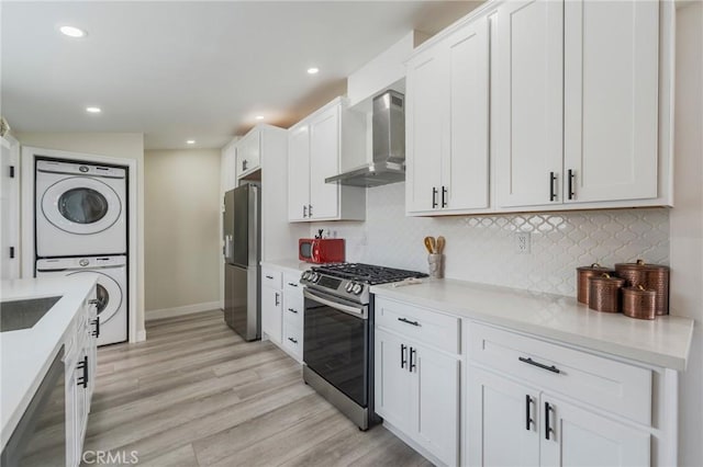 1925 W Beacon Ave, Anaheim, CA 92804 - kitchen with wall chimney exhaust hood, stainless steel appliances, stacked washer and clothes dryer, decorative backsplash, and white cabinetry