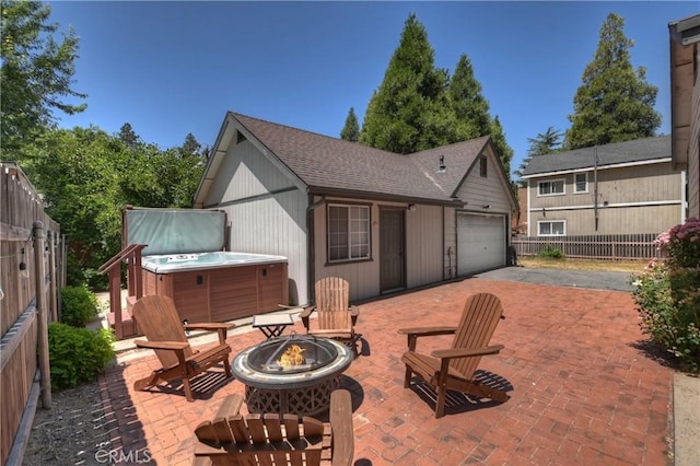 22989 Pine Ln, Crestline, CA 92325 - view of patio featuring a hot tub, a fire pit, driveway, and an attached garage