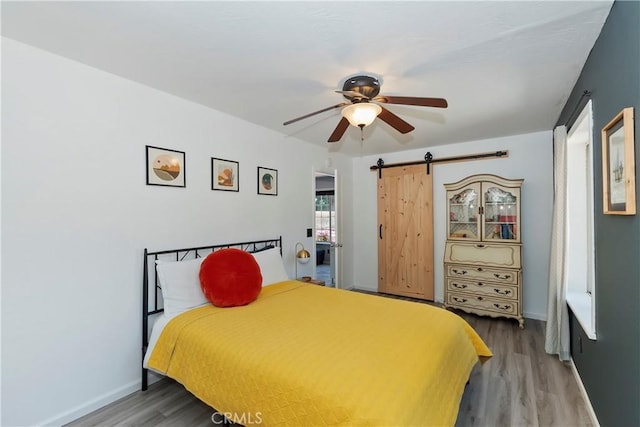 22989 Pine Ln, Crestline, CA 92325 - bedroom featuring wood finished floors, a barn door, and ceiling fan