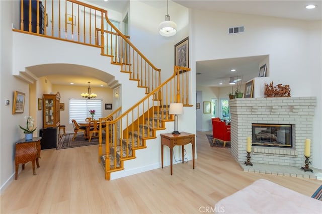 15535 Mallory Ct, Moorpark, CA 93021 - staircase featuring a high ceiling, wood finished floors, arched walkways, a brick fireplace, and a chandelier