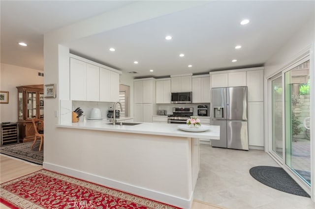 15535 Mallory Ct, Moorpark, CA 93021 - kitchen with stainless steel appliances, a peninsula, light countertops, recessed lighting, and white cabinetry