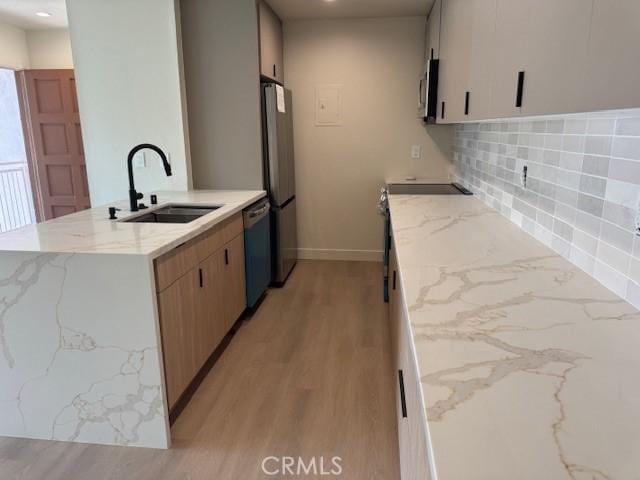 2501 W Sunflower Unit F12, Santa Ana, CA 92704 - kitchen featuring a peninsula, light stone counters, light wood-type flooring, and recessed lighting