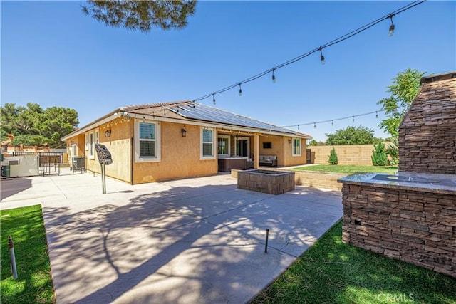 4664 Quartz Hill Rd, Quartz Hill, CA 93536 - back of house featuring a fenced backyard, roof mounted solar panels, stucco siding, and a patio area