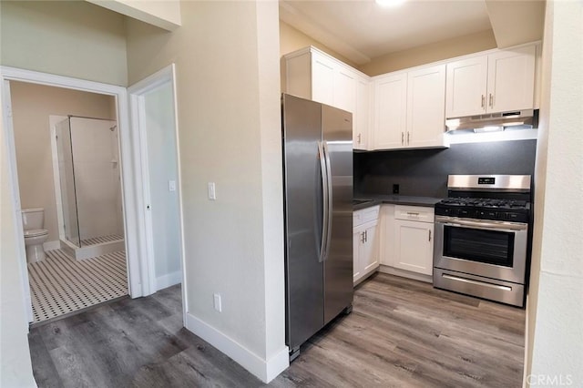 1703 Toberman St, Los Angeles, CA 90015 - kitchen featuring appliances with stainless steel finishes, white cabinetry, wood finished floors, under cabinet range hood, and dark countertops