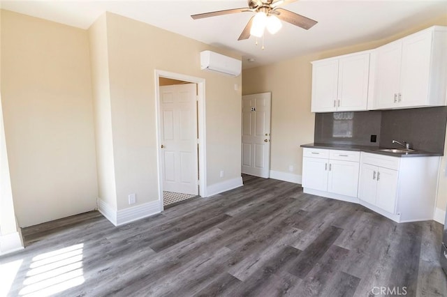 1703 Toberman St, Los Angeles, CA 90015 - kitchen with dark countertops, a ceiling fan, an AC wall unit, white cabinets, and dark wood-style floors