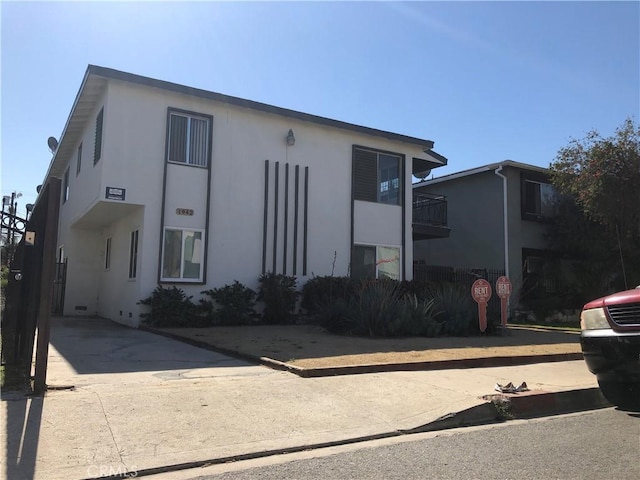 1942 S Sherbourne Dr, Los Angeles, CA 90034 - view of front facade with stucco siding, a balcony, and driveway