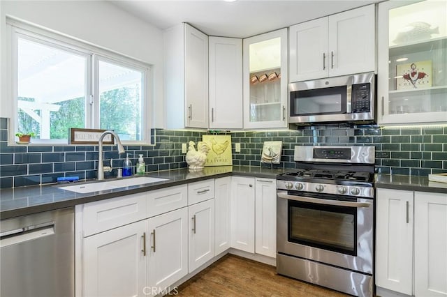 8042 Driftwood Dr, Huntington Beach, CA 92646 - kitchen featuring appliances with stainless steel finishes, dark countertops, white cabinetry, tasteful backsplash, and dark wood-type flooring
