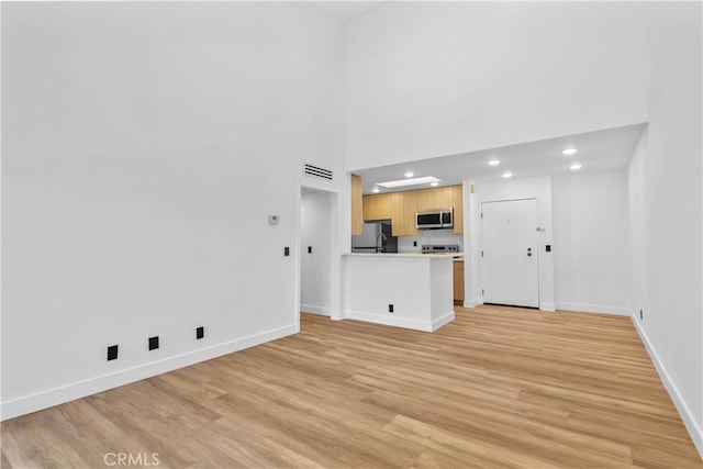 4210 Via Arbolada Unit 317, Los Angeles, CA 90042 - unfurnished living room with recessed lighting, light wood-type flooring, and a towering ceiling