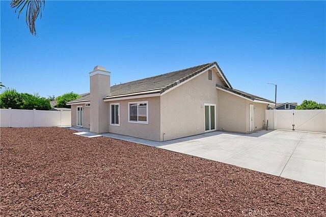 4004 Polk Ct, Chino, CA 91710 - back of property with a gate, a fenced backyard, a patio area, a chimney, and stucco siding