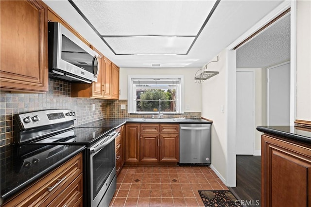 6741 Caro St, Paramount, CA 90723 - kitchen featuring stainless steel appliances, brown cabinetry, dark countertops, and decorative backsplash