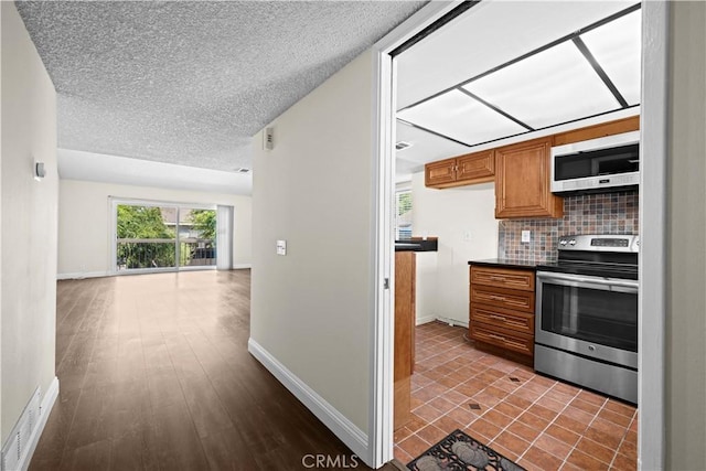 6741 Caro St, Paramount, CA 90723 - kitchen with electric stove, brown cabinets, a textured ceiling, tasteful backsplash, and dark countertops