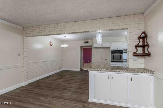 6000 Eugene Pl, Bakersfield, CA 93308 - kitchen featuring stainless steel oven, a textured ceiling, white cabinets, dark wood-style floors, and a peninsula