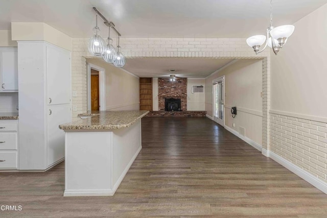 6000 Eugene Pl, Bakersfield, CA 93308 - unfurnished living room with a chandelier, dark wood-style floors, a fireplace, and brick wall