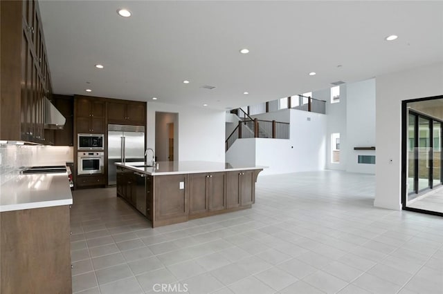 20552 Edgewood Ct, Chatsworth, CA 91311 - kitchen with built in appliances, wall chimney exhaust hood, light tile patterned floors, open floor plan, and light countertops