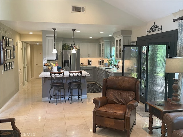 17 Thornbird, Aliso Viejo, CA 92656 - kitchen with stainless steel refrigerator with ice dispenser, gray cabinetry, a center island, light countertops, and glass insert cabinets