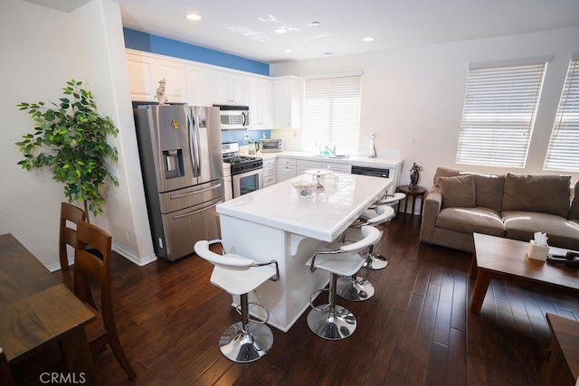 159 Principia Ct, Claremont, CA 91711 - kitchen with appliances with stainless steel finishes, a kitchen breakfast bar, a center island, white cabinetry, and dark wood-type flooring