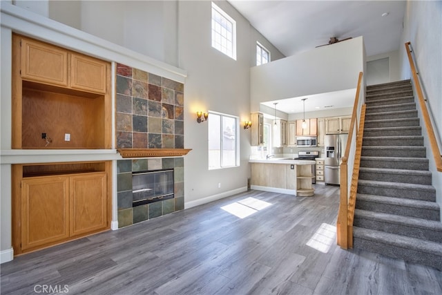 41808 Vardon Dr, Temecula, CA 92591 - unfurnished living room with stairway, wood finished floors, a tiled fireplace, and a towering ceiling