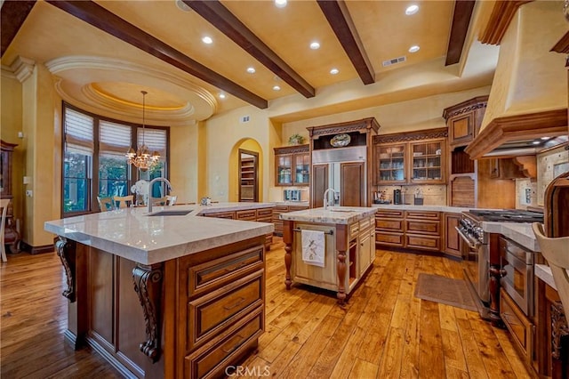 2882 Trovare Ct, Merced, CA 95340 - kitchen featuring a large island with sink, beam ceiling, light wood-style flooring, premium range hood, and high quality appliances