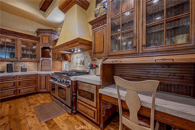 2882 Trovare Ct, Merced, CA 95340 - kitchen with appliances with stainless steel finishes, custom exhaust hood, tasteful backsplash, light countertops, and brown cabinets