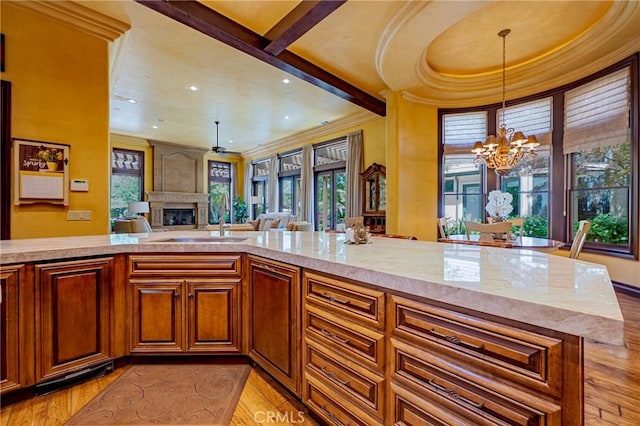 2882 Trovare Ct, Merced, CA 95340 - kitchen with light wood finished floors, a chandelier, a large fireplace, decorative light fixtures, and light stone countertops