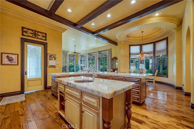 2882 Trovare Ct, Merced, CA 95340 - kitchen featuring a center island with sink, ornamental molding, hardwood / wood-style flooring, beam ceiling, and a chandelier
