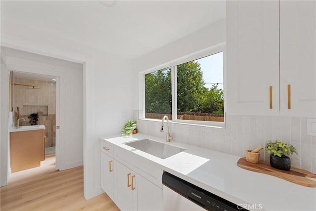 2158 10th St, Riverside, CA 92507 - kitchen featuring white cabinets, light countertops, light wood-style floors, dishwashing machine, and decorative backsplash