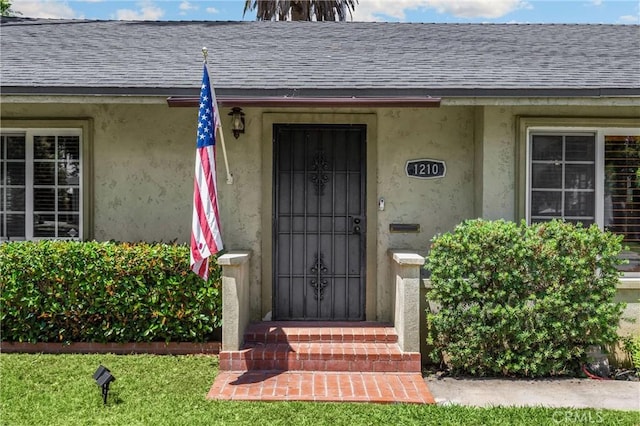 1210 W Marshall Blvd, San Bernardino, CA 92405 - doorway to property featuring a shingled roof and stucco siding