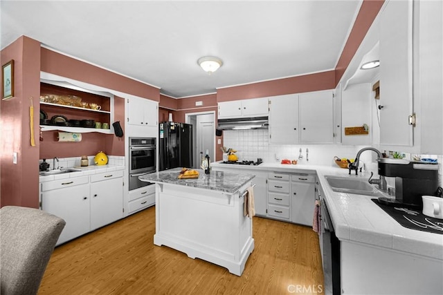 1210 W Marshall Blvd, San Bernardino, CA 92405 - kitchen with black appliances, under cabinet range hood, white cabinets, and light wood-style flooring