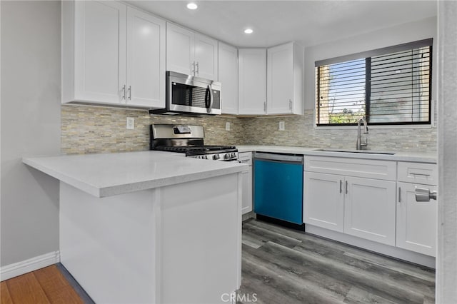 2621 E 20th St Unit 12, Signal Hill, CA 90755 - kitchen featuring appliances with stainless steel finishes, white cabinets, a peninsula, dark wood-style floors, and recessed lighting