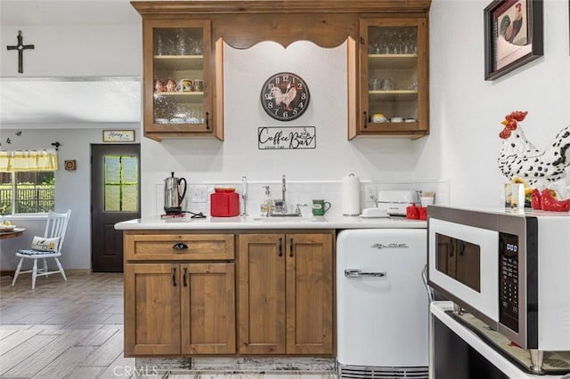 4742 Crow Rd, Oakdale, CA 95361 - kitchen with light countertops, brown cabinetry, glass insert cabinets, and crown molding