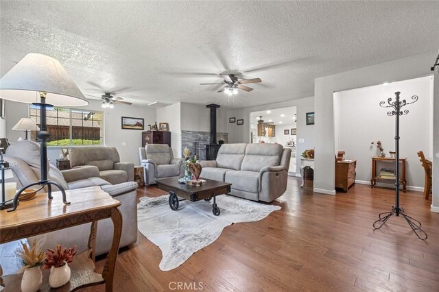 4742 Crow Rd, Oakdale, CA 95361 - living area with a ceiling fan, a wood stove, wood finished floors, and a textured ceiling