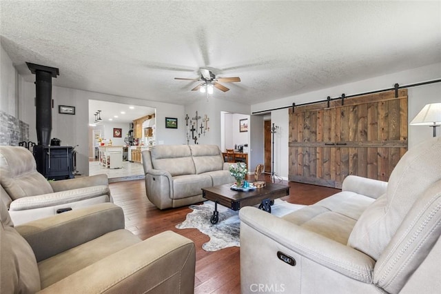 4742 Crow Rd, Oakdale, CA 95361 - living area featuring a barn door, a wood stove, a ceiling fan, wood finished floors, and a textured ceiling