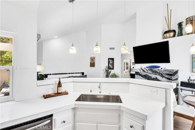 2 Daytona Unit 129, Laguna Niguel, CA 92677 - kitchen featuring dishwashing machine, light countertops, white cabinets, high vaulted ceiling, and decorative light fixtures