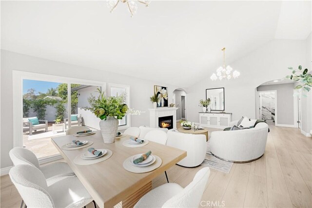 25981 Cordillera Dr, Mission Viejo, CA 92691 - dining room with arched walkways, a chandelier, a glass covered fireplace, vaulted ceiling, and light wood-style floors