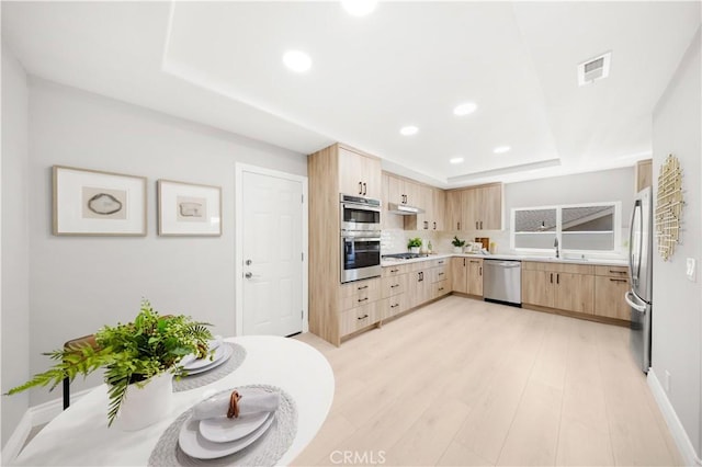25981 Cordillera Dr, Mission Viejo, CA 92691 - kitchen with light brown cabinetry, appliances with stainless steel finishes, a tray ceiling, backsplash, and recessed lighting
