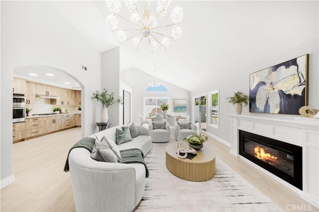 25981 Cordillera Dr, Mission Viejo, CA 92691 - living room with arched walkways, a chandelier, light wood-style flooring, high vaulted ceiling, and a glass covered fireplace