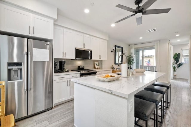1201 Via Lucero, Oceanside, CA 92056 - kitchen with stainless steel appliances, an island with sink, white cabinets, a kitchen bar, and recessed lighting