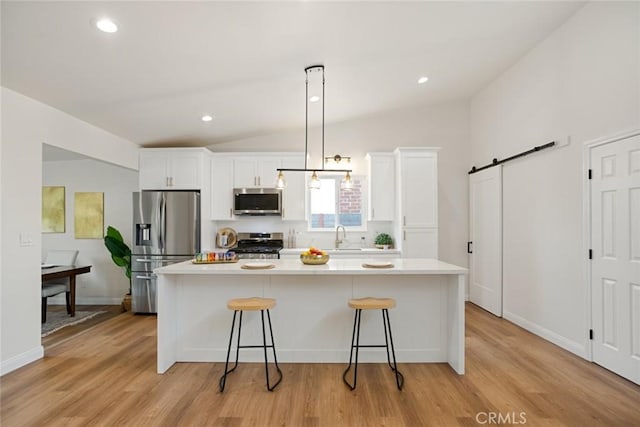 6118 Wolfe St, Lakewood, CA 90713 - kitchen featuring appliances with stainless steel finishes, white cabinetry, a barn door, a kitchen breakfast bar, and vaulted ceiling