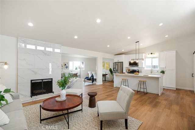 6118 Wolfe St, Lakewood, CA 90713 - living room featuring light wood-style floors, lofted ceiling, a high end fireplace, and recessed lighting