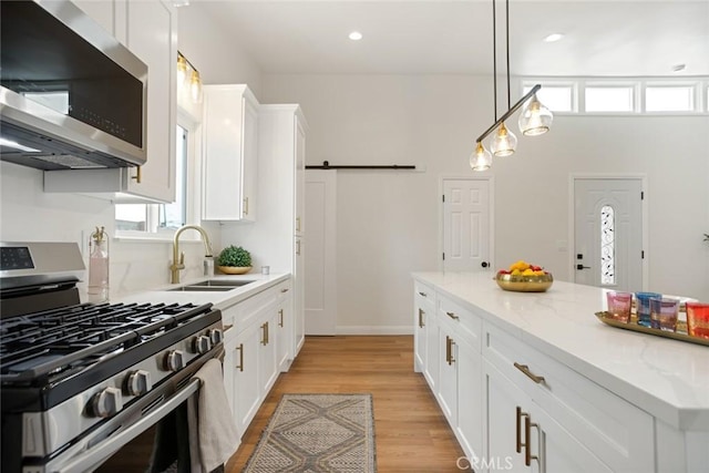 6118 Wolfe St, Lakewood, CA 90713 - kitchen with appliances with stainless steel finishes, white cabinetry, light wood finished floors, light stone counters, and decorative light fixtures