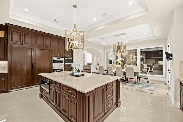 300 W Las Flores Ave, Arcadia, CA 91007 - kitchen featuring a chandelier, a tray ceiling, arched walkways, light countertops, and hanging light fixtures