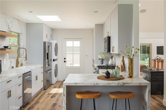 212 E 19th St, Costa Mesa, CA 92627 - kitchen with appliances with stainless steel finishes, a skylight, a breakfast bar area, and light wood-type flooring