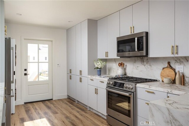 212 E 19th St, Costa Mesa, CA 92627 - kitchen featuring stainless steel appliances, light wood-style flooring, backsplash, light stone counters, and white cabinets