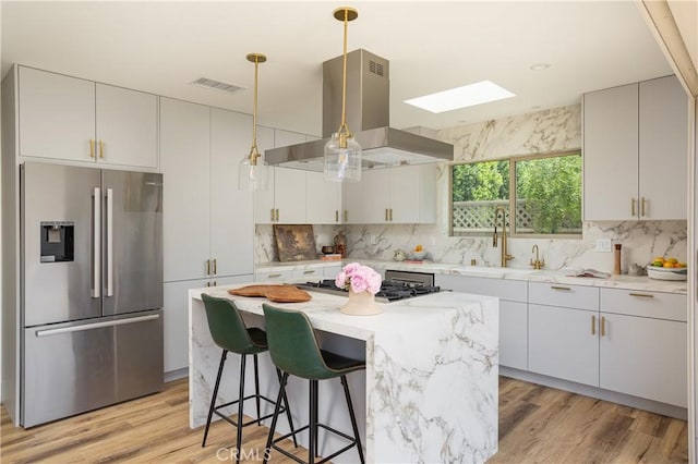 212 E 19th St, Costa Mesa, CA 92627 - kitchen with stainless steel appliances, island exhaust hood, a skylight, and light wood finished floors