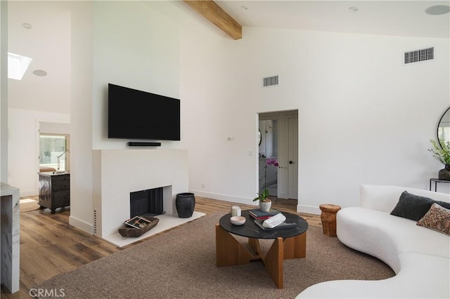 212 E 19th St, Costa Mesa, CA 92627 - living room featuring high vaulted ceiling, a skylight, wood finished floors, beamed ceiling, and a fireplace with flush hearth